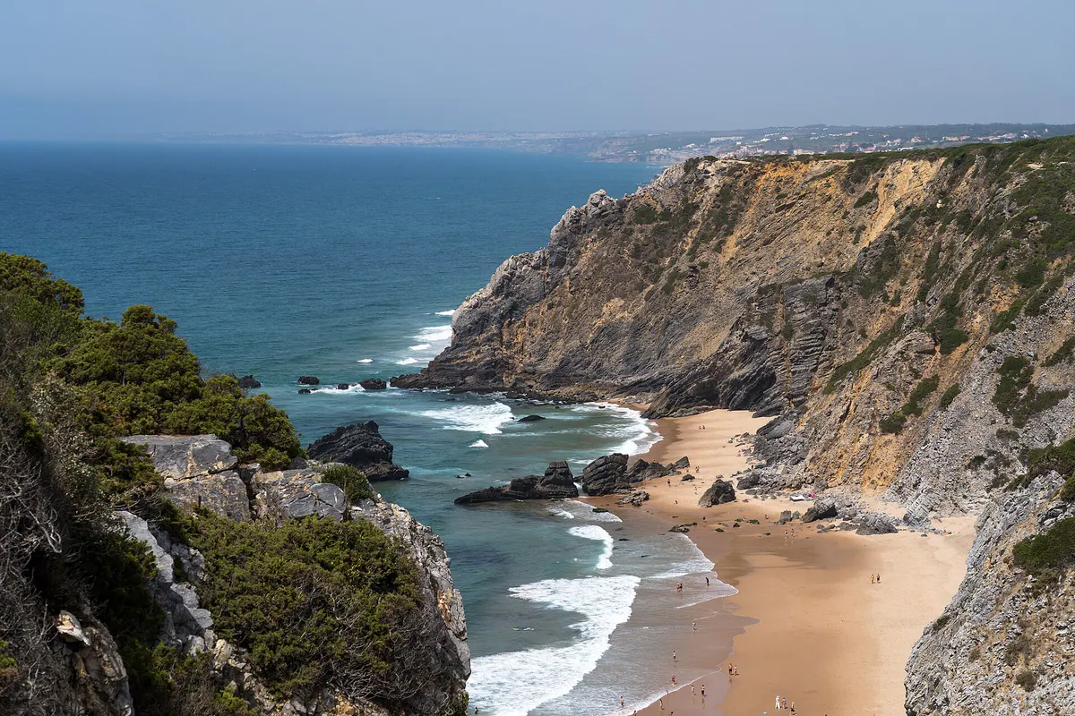 Praia da Adraga’s golden cove between ochre cliffs