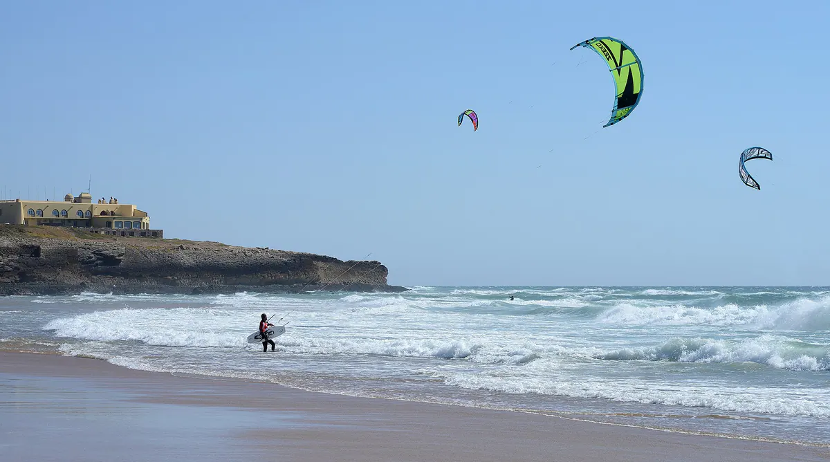 Kitesurfing at Guincho beach, a green kite above the waves