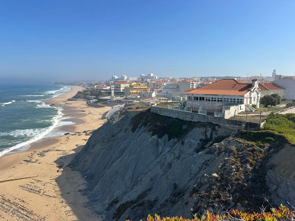 Praia das Maçãs: wide sand and the village on the cliffs under a blue sky