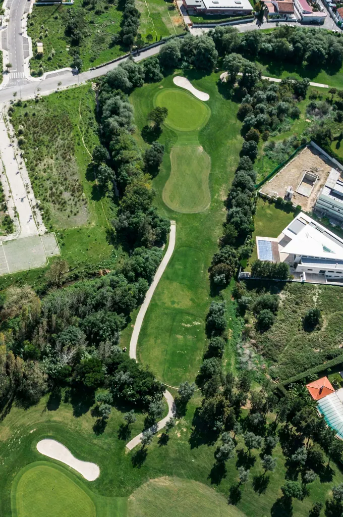Aerial view of a contemporary house with a pool beside a green in Beloura