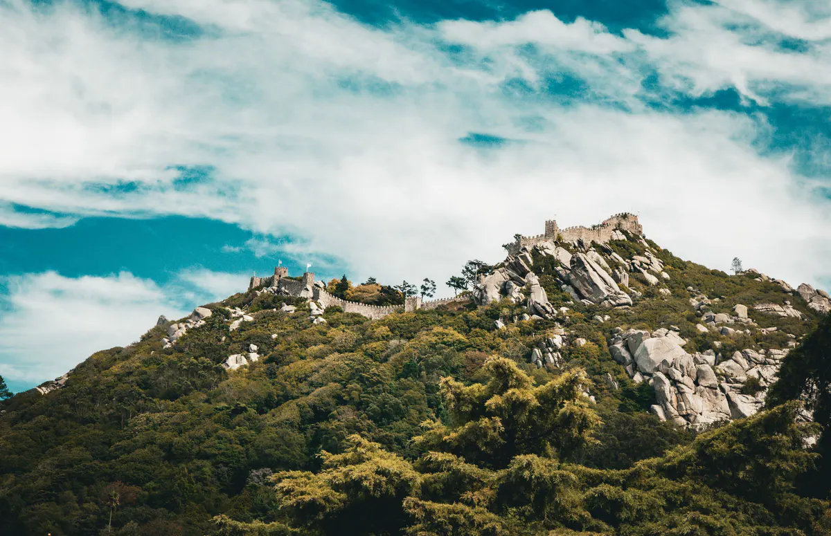 The walls of the Moorish Castle along a green ridge of the Sintra hills