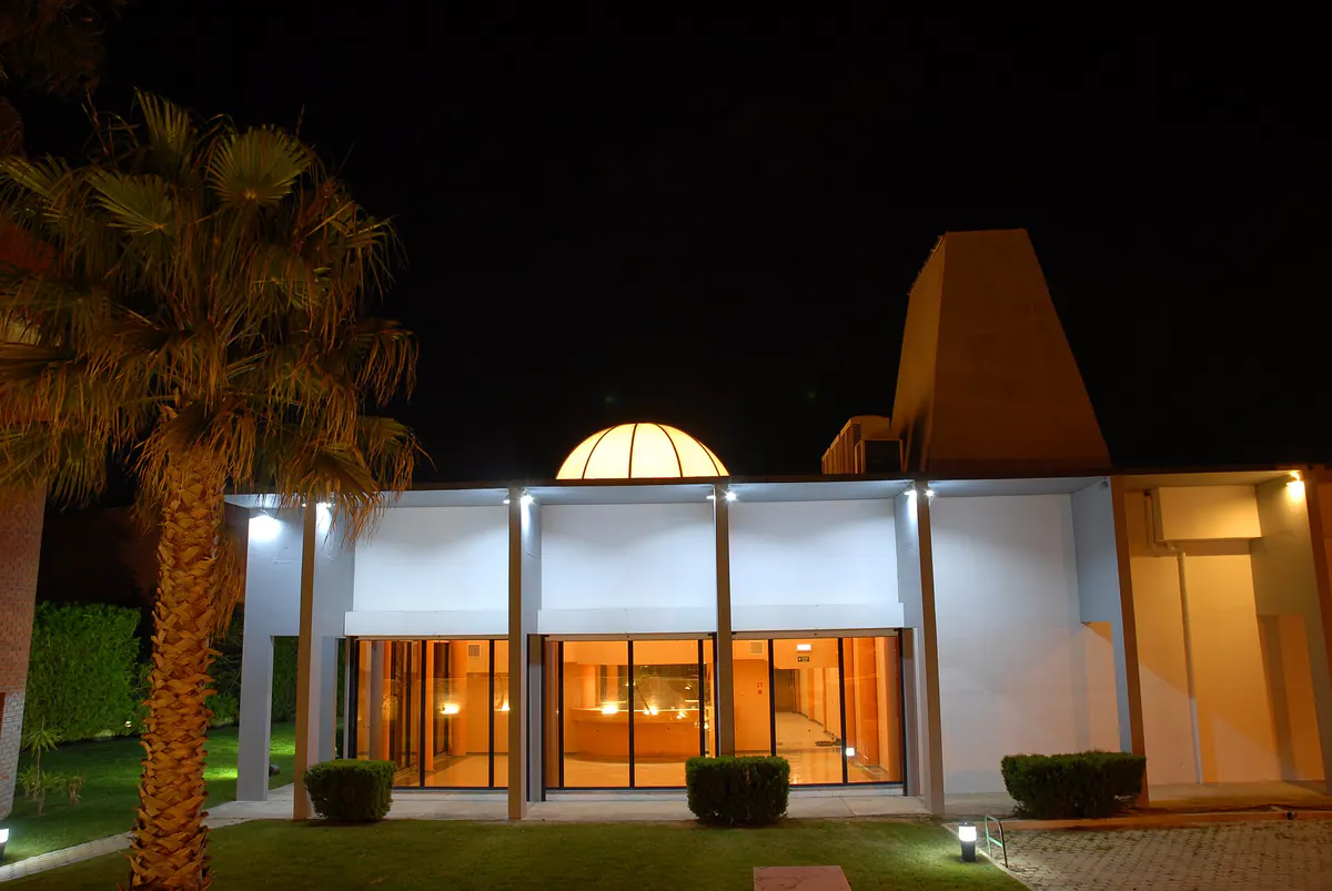 Quinta das Cruzadas in Beloura, lit up at night beside a palm tree
