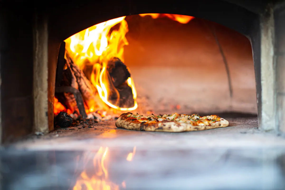 An artisan pizza baking in a wood-fired oven