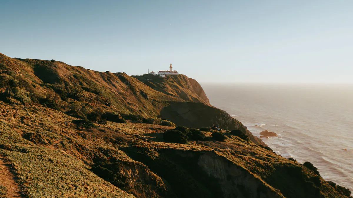 Cabo da Roca lighthouse on green cliffs in evening light