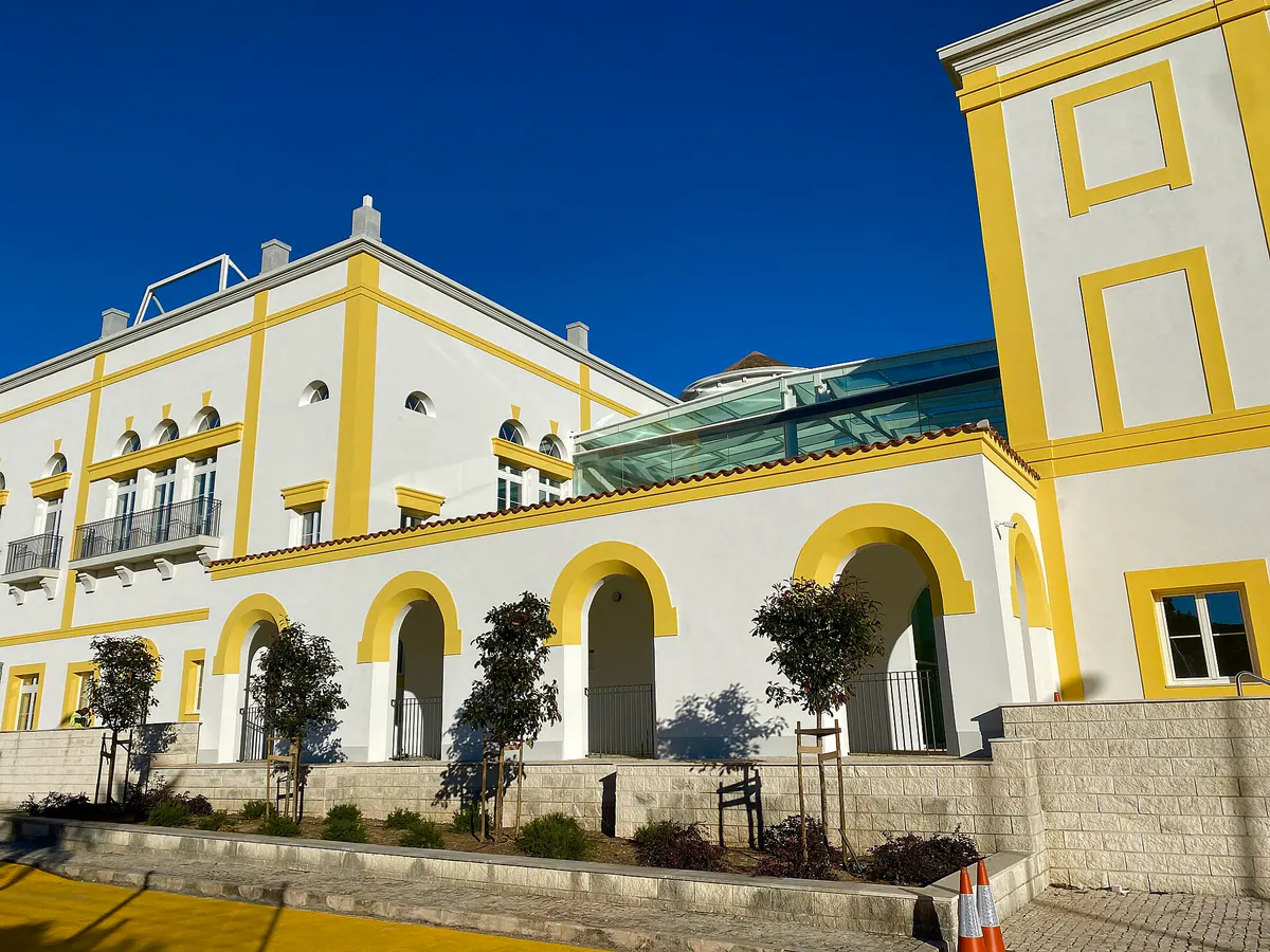The TASIS Portugal building, with white and yellow arcades under a blue sky